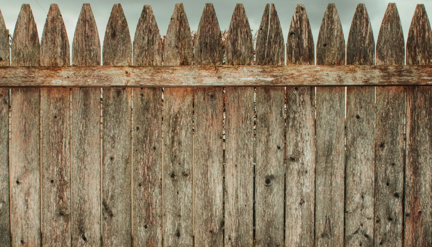 A grey, weathered old wooden fence at the end of its life