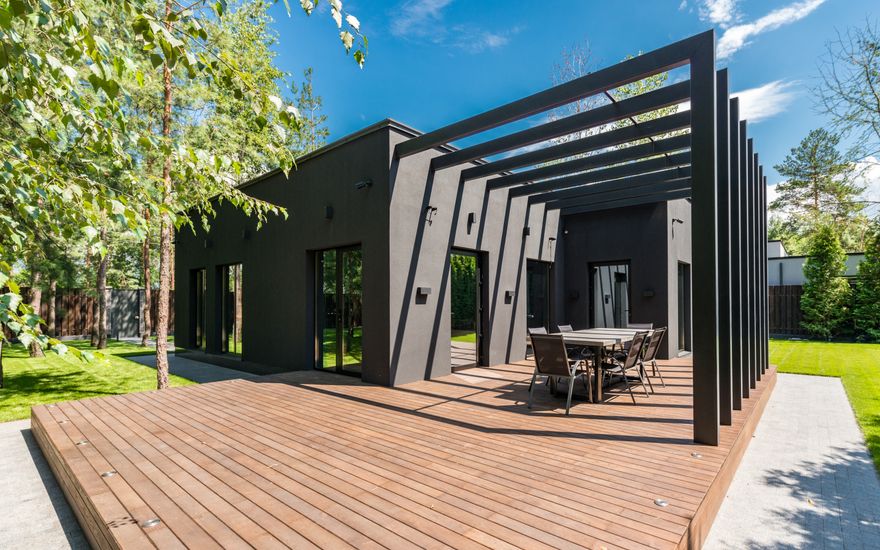 Large timber deck with a pergola beside a modern house