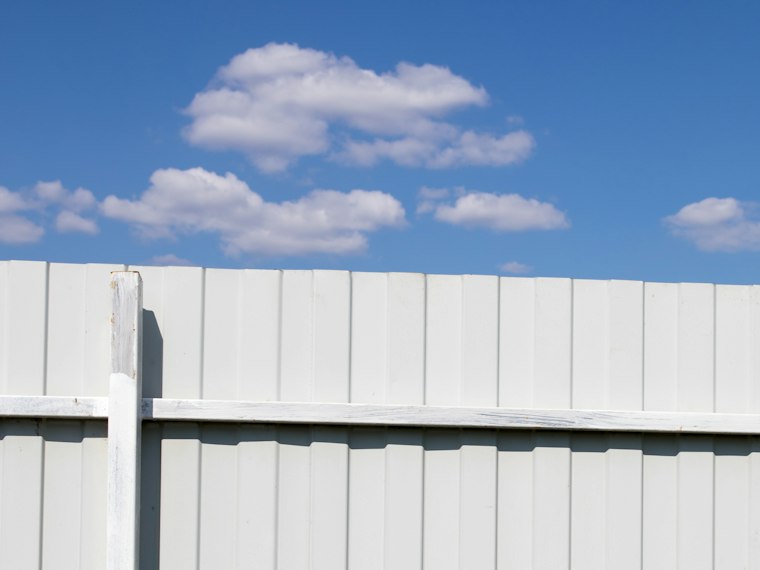 White vinyl privacy fence against a blue sky