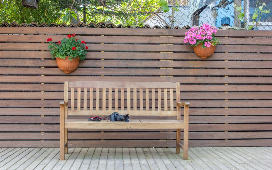 Modern horizontal slat fence behind a timber bench and planters