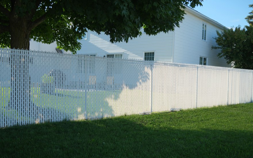 White vinyl privacy fence along the side of a suburban house